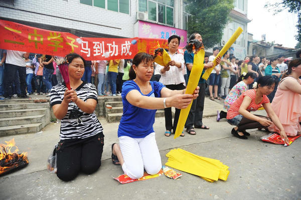 　送考家長和村民燒紙跪拜,。