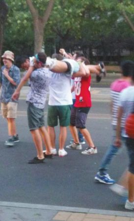 四名外籍男子一同扛起醉漢拍照,。