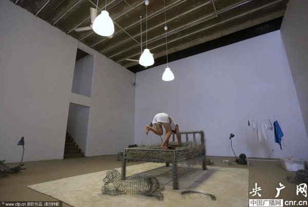 　2014年8月11日,，北京,，中國女藝術(shù)家周潔在北京現(xiàn)在畫廊的展廳睡在一個(gè)未完成的鐵絲床上，這一藝術(shù)項(xiàng)目被命名為“36天”,，而這36天里,，她可以正常進(jìn)食、洗漱,、如廁,，以及玩手機(jī)等。