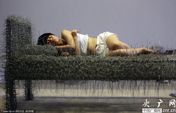 2014年8月11日，北京,，中國女藝術(shù)家周潔在北京現(xiàn)在畫廊的展廳睡在一個未完成的鐵絲床上,，這一藝術(shù)項目被命名為“36天”,，而這36天里,，她可以正常進食,、洗漱,、如廁,，以及玩手機等。