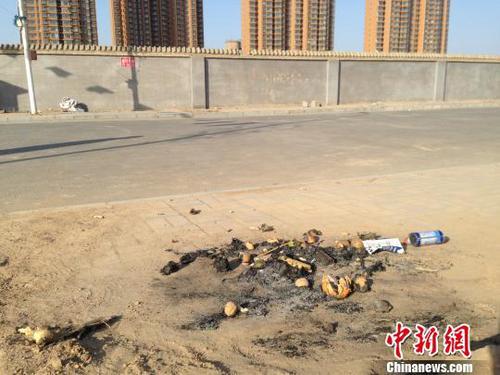 親人在何建華遇害處燃燒的紙錢和祭品,。 王天譯 攝
