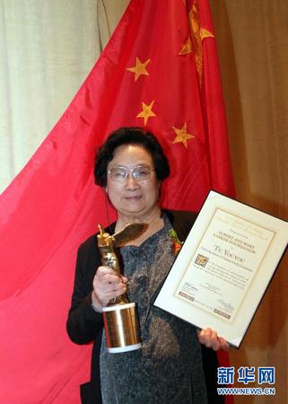 這是2011年9月23日,，屠呦呦在美國(guó)紐約舉行的拉斯克獎(jiǎng)?lì)C獎(jiǎng)儀式上展示獎(jiǎng)杯和證書(shū)。
