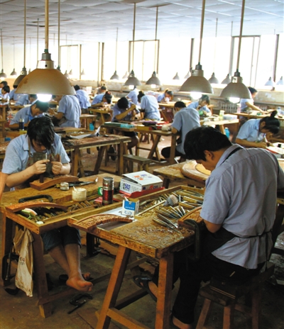 紅木家具廠內,，工人正在進行雕刻,。京作家具繼承了明式家具結構造型方面的優(yōu)點,，更加突出了雕刻裝飾功能,。資料圖片