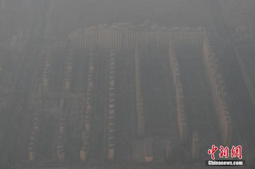 資料圖：2015年12月21日,，北京上空航拍空氣重污染,，地面建筑若隱若現(xiàn)。12月18日,，北京再次發(fā)布紅色預(yù)警,，12月19日7時至12月22日24時啟動空氣重污染紅色預(yù)警措施。實(shí)施機(jī)動車單雙號行駛,、建議中小學(xué)幼兒園停課等措施,。 <a target='_blank' href='http://www.chinanews.com/'>中新社</a>記者 廖攀 攝
