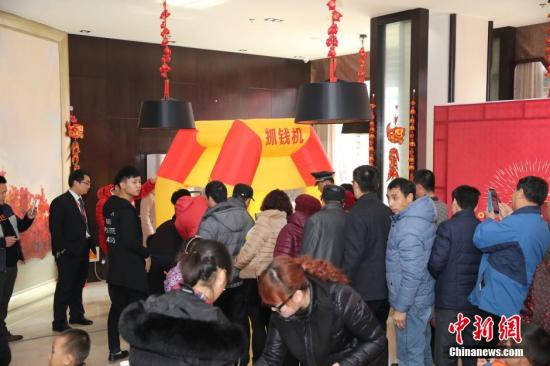 資料圖：2016年2月27日，山東東營,，看房的市民在商家設(shè)置的“搶錢機”內(nèi)搶著飛舞的人民幣,，搶到的人民幣歸市民所有。由于房地產(chǎn)市場低迷,，山東東營的某樓盤為了吸引前來看房的市民,，在售樓處安裝了“搶錢機”，看房的市民排成長隊“搶錢”,，用真金白銀刺激看房客,。 圖片來源：視覺中國