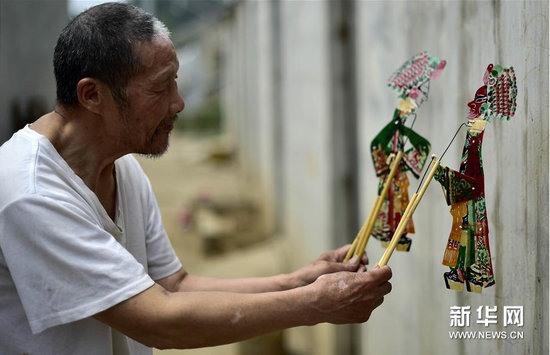 6月5日,，張奎老人在屋外的墻上耍皮影