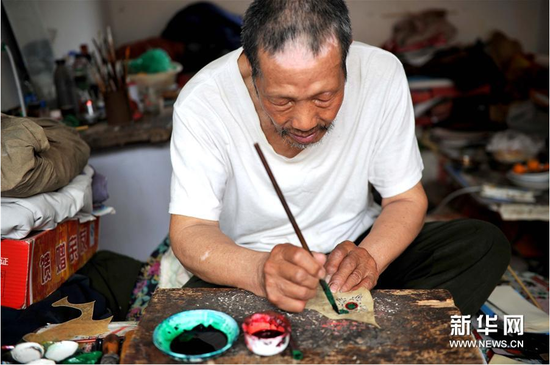 6月5日,，張奎老人在為雕刻好的皮影上色