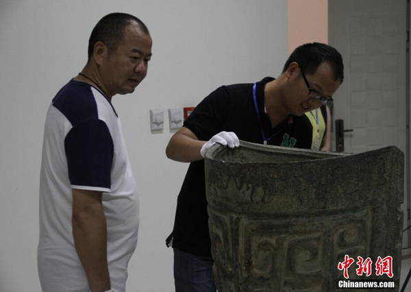 參展博物館代表檢查文物“象紋大銅鐃”,。 中新社記者 鐘欣 攝