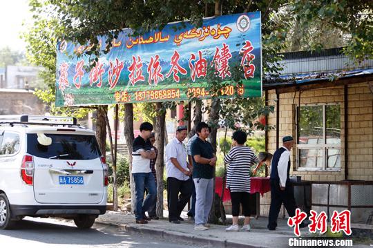每天前來(lái)買(mǎi)馕的人在馕炕前排隊(duì)?！⊥跣≤?攝