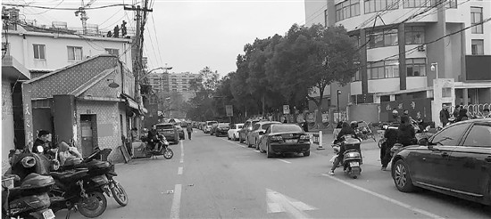 上下學期間，西行路無論機動車非機動車都不允許停靠,。白色圍欄是學生在校門和停車場之間的“安全通道”,。溫雨昕 攝