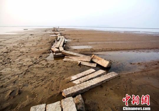 　　近年來,，當鄱陽湖水位下降至枯水位時，石橋就會露出水面,，成為當?shù)匾痪?。圖為游人在古橋上行走。12月23日攝　傅建斌　攝