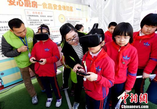 活動現(xiàn)場，小學生通過VR(虛擬現(xiàn)實)技術(shù)設(shè)備模擬廚房場景,，在互動中學習生熟分開,，菜品搭配與油鹽使用的廚房食品安全知識?！∮浾邉⒖筛?攝
