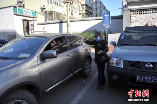 今年元月起，北京全市3000多名路側(cè)停車管理員上崗證更換,，新上崗證標(biāo)有二維碼,，市民用手機掃描即可看到管理員的照片、姓名,、所在公司,、監(jiān)督電話等詳細(xì)信息。若冒用或偽造,，掃描出來的信息將與實際不符,，一旦遇到假收費員，市民有權(quán)拒絕交費,。圖為停車場管理員張大姐為車主指揮倒車,。<a target='_blank' href='http://www.chinanews.com/' >中新網(wǎng)</a>記者 金碩 攝