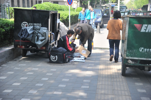 圖為快遞小哥在路邊配送快遞,。呂春榮 攝