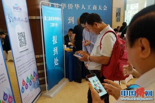 第二屆華僑華人工商大會報到現(xiàn)場，中國新聞社“僑寶”客戶端及中國僑網(wǎng)微信宣傳品吸引了高度關(guān)注,，嘉賓紛紛掃碼下載。付強 攝