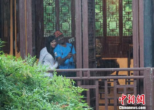 中國(guó)僑網(wǎng)雨中，到訪無(wú)錫的外籍人士在寄暢園中玩起了自拍?！O權(quán)　攝