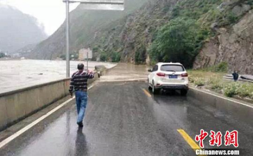 四川某地道路被淹沒交通中斷,，過(guò)往路人和車輛通行受阻,。　鐘欣 攝