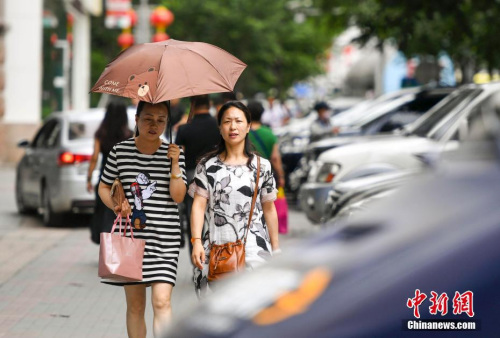 新疆烏魯木齊市街頭,，民眾打傘抵擋高溫天氣。