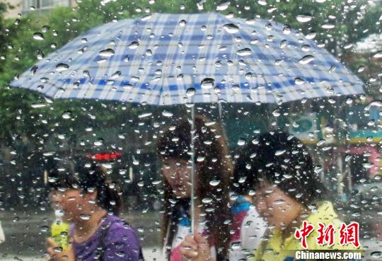 6月28日，隔著滴滿雨珠的車窗,，打著雨傘的市民在南京街頭經(jīng)過,。泱波　攝
