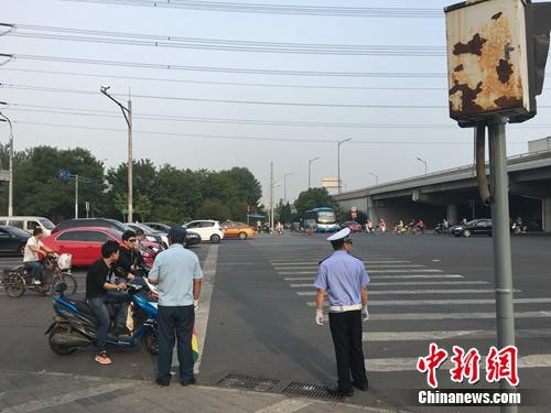 6月21日上午,，北京仰山橋下十字路口,，執(zhí)勤人員要求非機動車停在停止線后。湯琪 攝