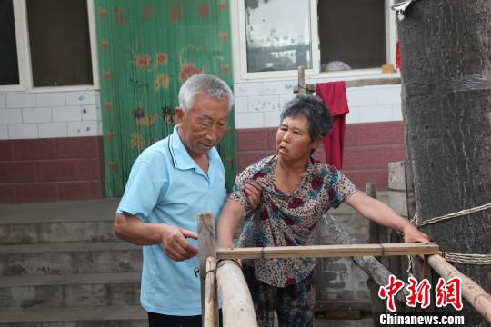 為讓妻子慢慢學(xué)會(huì)走路，李文生每天扶著妻子一遍一遍練習(xí)走路,?！±钤杭t 攝