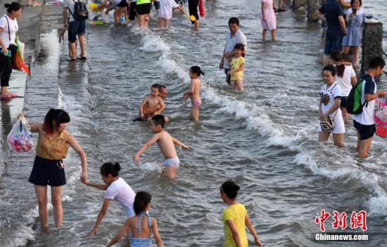 7月4日傍晚,，市民們帶著小孩在海邊戲水消暑,。連日來，受副熱帶高壓影響廈門地區(qū)持續(xù)高溫,。 張斌 攝