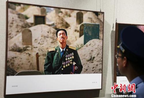 一名部隊(duì)官兵正在欣賞攝影作品《英雄探妻》?！⒄祭?攝