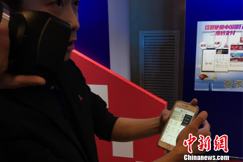 一位工作人員正在教體驗(yàn)者使用云閃付產(chǎn)品,。<a target='_blank' href='http://www.chinanews.com/' >中新網(wǎng)</a> 種卿 攝