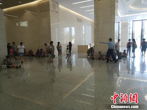 軍博一層大廳也有一些參觀者坐在地上,，工作人員正在勸他們不要席地而坐,。上官云 攝