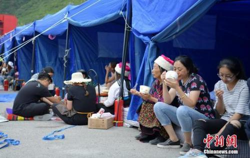 8月10日,，四川九寨溝“8.8”地震震源中心附近的臨時(shí)安置點(diǎn),，受災(zāi)村民在帳篷邊吃飯。中新社記者 劉忠俊 攝