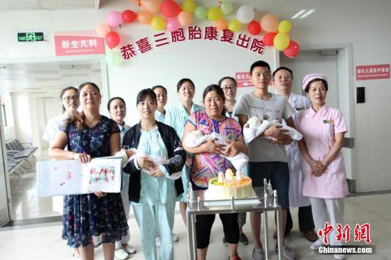 圖為醫(yī)護(hù)人員和三胞胎及家人合影,。 鐘欣 攝