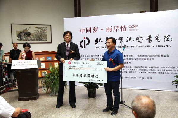 9月29日，在中國夢·兩岸情畫展開幕式上,，民革株洲市委主委劉春正在接受北京正舉沈鵬書畫院院長沈鵬的義賣捐贈,。
