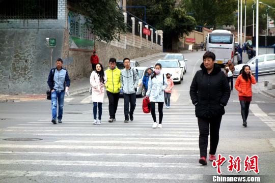 圖為市民們穿著棉服,、羽絨服在寒風(fēng)中卷縮著過馬路,。　孫睿 攝