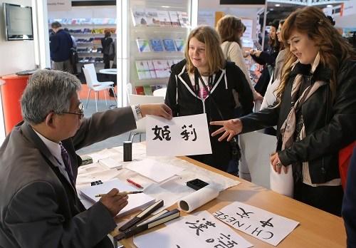 中國(guó)僑網(wǎng)資料圖：在英國(guó)倫敦奧林匹亞展覽中心舉行的英國(guó)語(yǔ)言展上，中國(guó)展臺(tái)的工作人員展示中國(guó)書(shū)法,。新華社記者 殷剛 攝