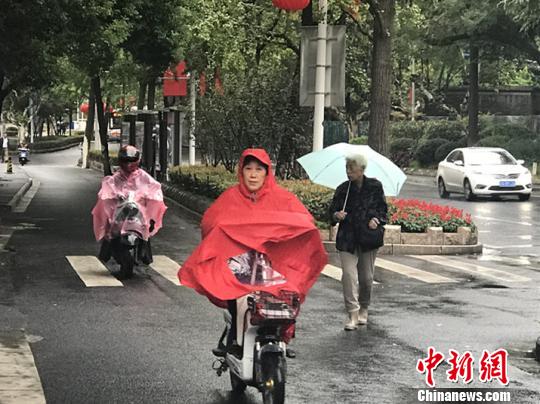 11日,，南京迎來降溫降雨。圖為市民披上雨衣出行,?！铑伌?攝