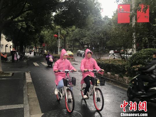 11日,，南京迎來降溫降雨,。圖為市民披上雨衣出行?！铑伌?攝