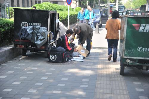 圖為快遞小哥在路邊配送快遞,。呂春榮 攝