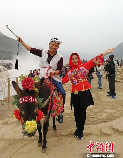 緬甸南坎明德學(xué)校的負(fù)責(zé)人楊蜜蜜與弟弟楊彪在黃河岸邊穿上極具地方特色的服飾,，騎著毛驢合影留念?！罱苡?攝