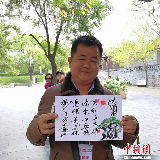 緬甸大其力大華學(xué)校負(fù)責(zé)人楊恩源在洪洞大槐樹(shù)景區(qū)向記者展示自己姓氏的文創(chuàng)產(chǎn)品,。　楊杰英 攝
