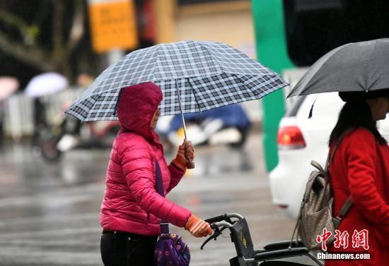 資料圖：昆明市區(qū)里身著羽絨服冒雨趕路的民眾,。 中新社記者 李進(jìn)紅 攝
