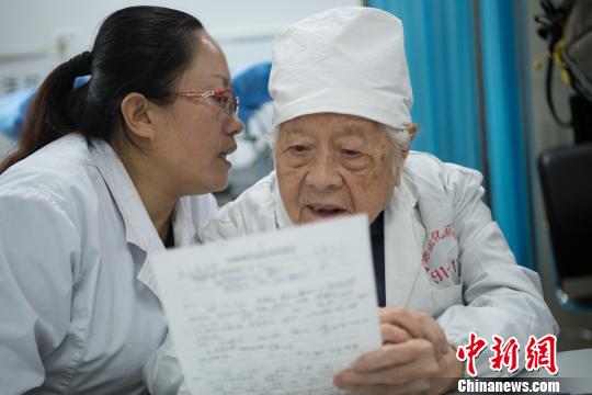 問診時(shí),，她的助手王利花趴在于載畿耳朵旁當(dāng)“傳聲筒”，書寫病歷時(shí),，于載畿用尺子比著,。　武俊杰 攝
