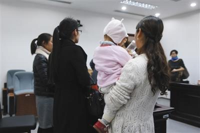 昨日,，一名當(dāng)事女員工抱著孩子在法庭上接受記者采訪。新京報(bào)記者 王貴彬 攝