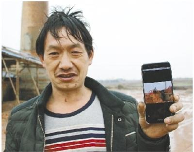 1月27日，嚴(yán)國有向記者展示他手機(jī)上的照片——老板用來抵工資的大量紅磚?，F(xiàn)在,，他身后堆放紅磚的地方已經(jīng)成了空地。
