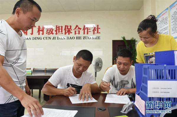 兩名村民在福建武平縣城廂鎮(zhèn)園丁村村級擔(dān)保合作社簽訂反擔(dān)保合同（2017年6月15日攝）。