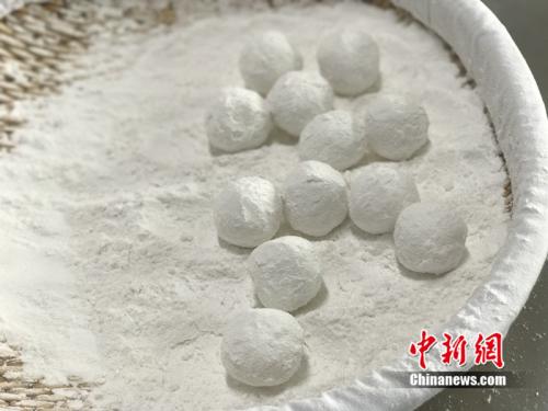 "制作元宵時(shí)，首先要將餡料做好,，沾上水,，再投進(jìn)盛滿糯米粉的笸籮內(nèi)搖。<a