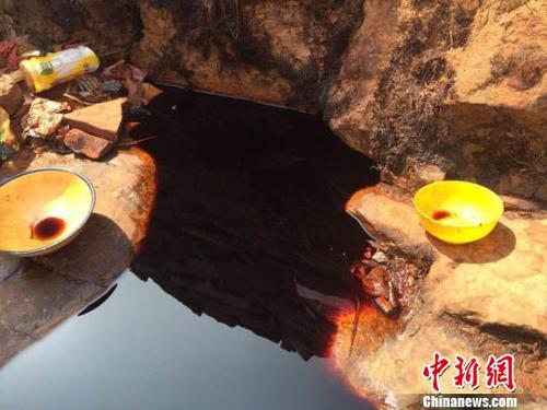 從石崖縫隙里滲出的黑褐色不明液體,，從顏色看如醬油狀,。　劉鵬 攝