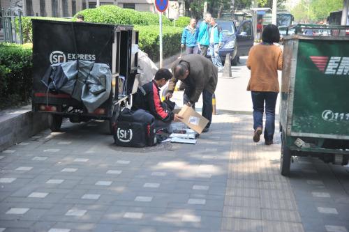 圖為快遞小哥在路邊配送快遞,。呂春榮 攝