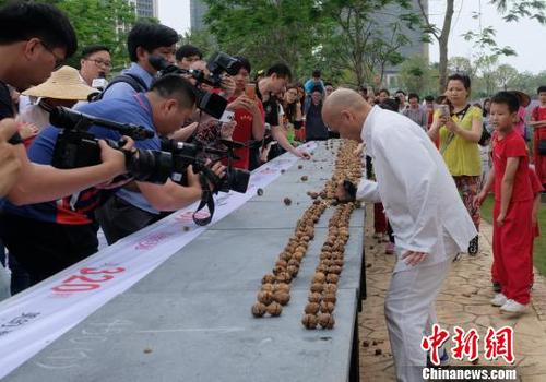 黎偉軍手劈核桃現(xiàn)場吸引不少人圍觀?！〕叹皞?攝