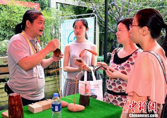 臺(tái)灣雕刻藝術(shù)家,、臺(tái)灣木戀石文化藝術(shù)有限公司創(chuàng)辦人黃守堃(左一)向觀眾介紹自己的雕刻作品,。記者劉可耕 攝