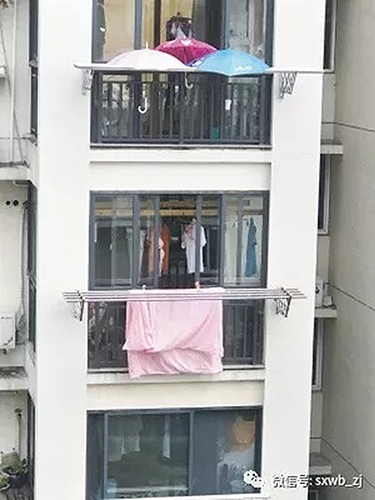 下雨了樓下被子還曬在外面:樓上住戶在陽(yáng)臺(tái)撐3把傘